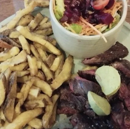 Une assiette de viande, frites et salade